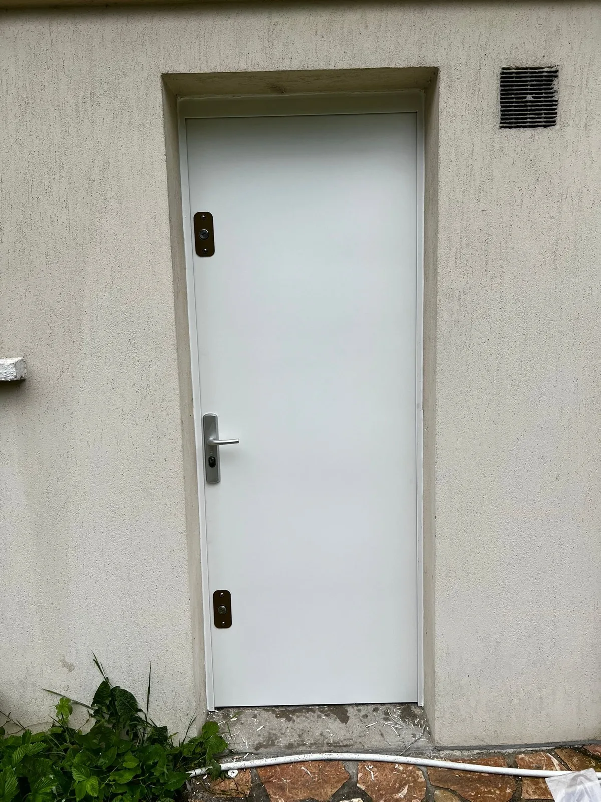 Porte blanche dans un mur enduit en extérieur avenue Desfeux à Boulogne-Billancourt, deux entrées de serrure noires visibles