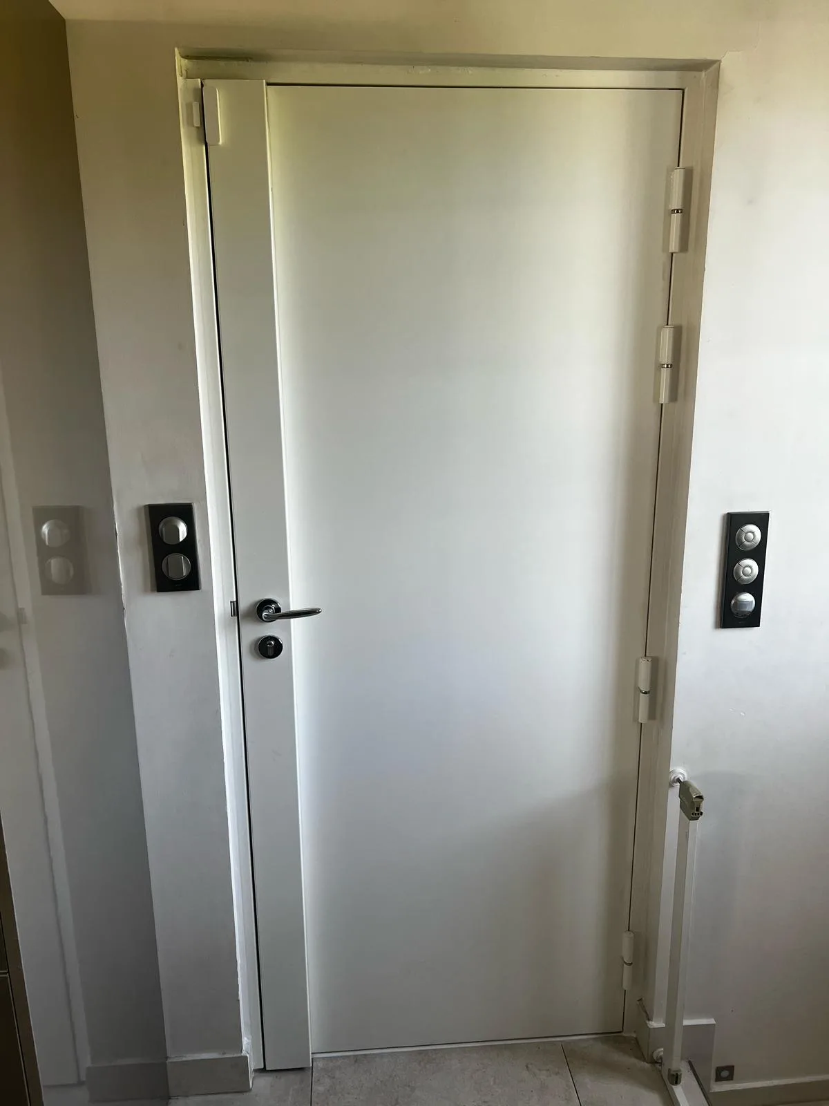Porte d'entrée claire entrouverte rue de la Belle Feuille à Boulogne-Billancourt, pênes de la serrure multipoints visibles sur le chant