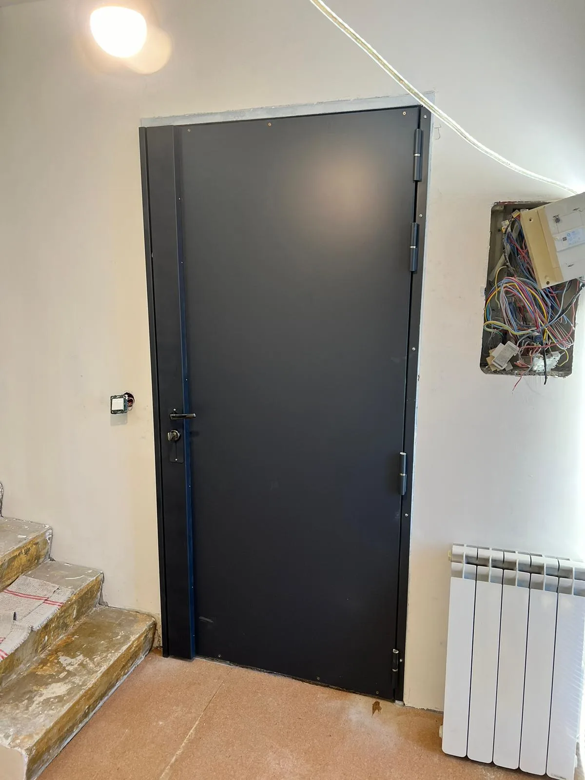 Porte bleu nuit en haut de quelques marches carrelées, rue Blondeau à Boulogne-Billancourt, après pose d'un blindage