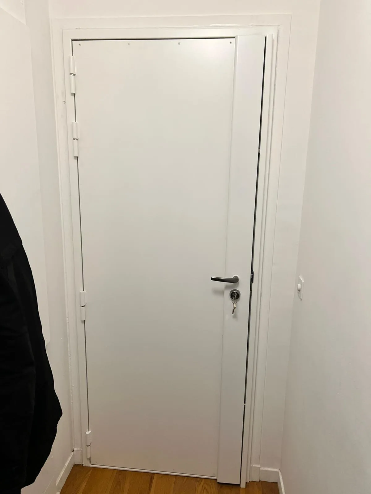 Porte blindée blanche entrouverte rue Jules Henripre à Boulogne-Billancourt, renforts visibles sur le chant