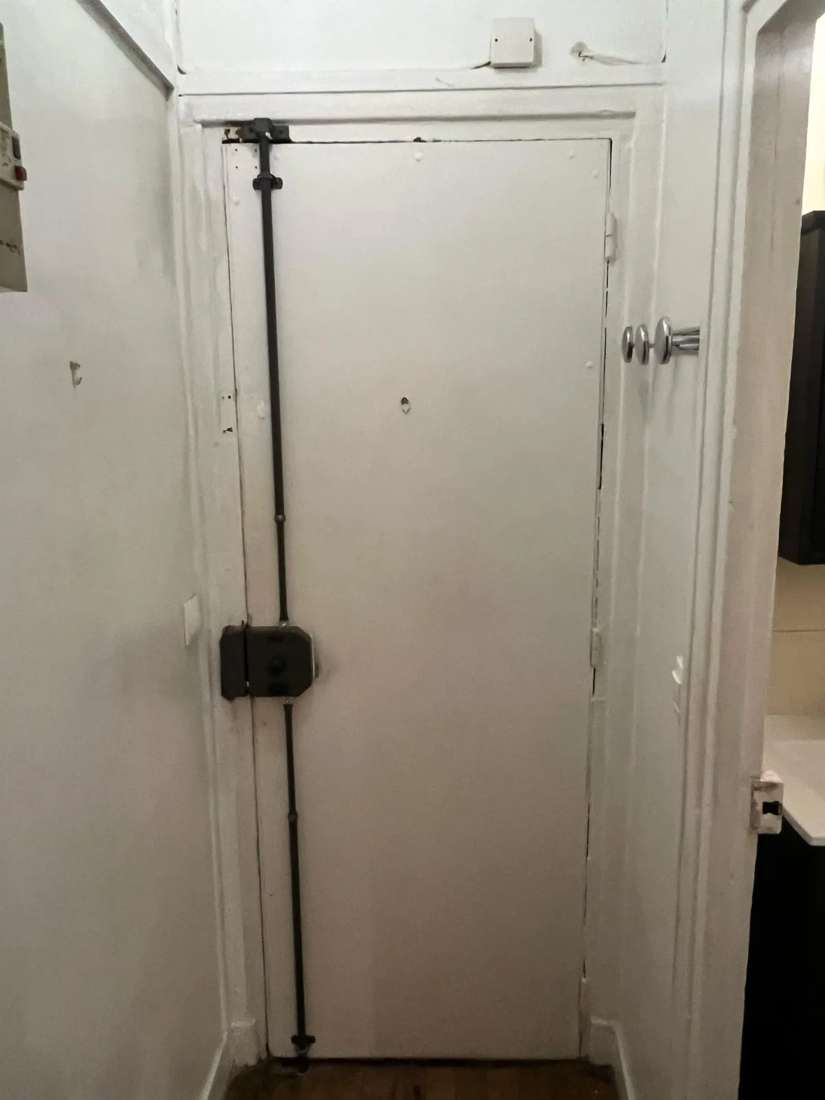 Porte blanche équipée d'une barre de fermeture verticale noire, rue de la Pyramide à Boulogne-Billancourt