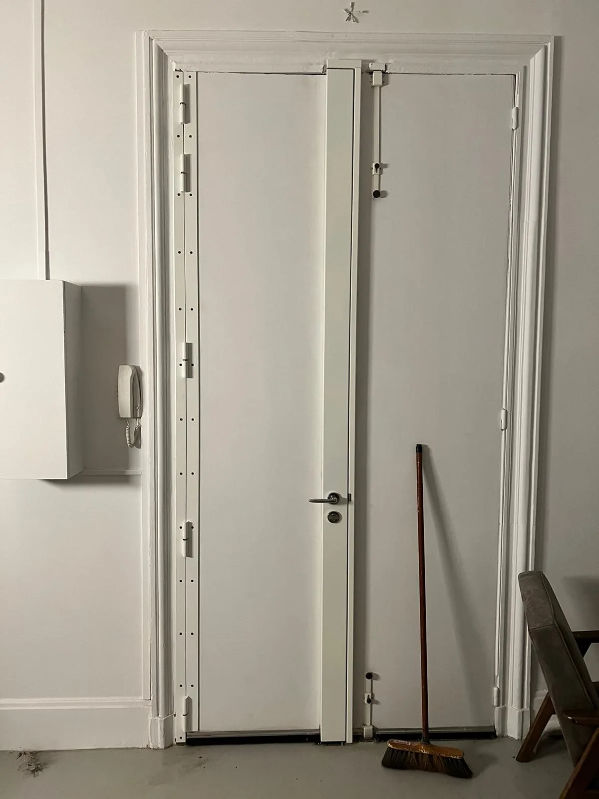 Porte à deux vantaux ouverte rue Jean Mermoz à Boulogne-Billancourt, barre de pivot et tringlerie verticale apparentes