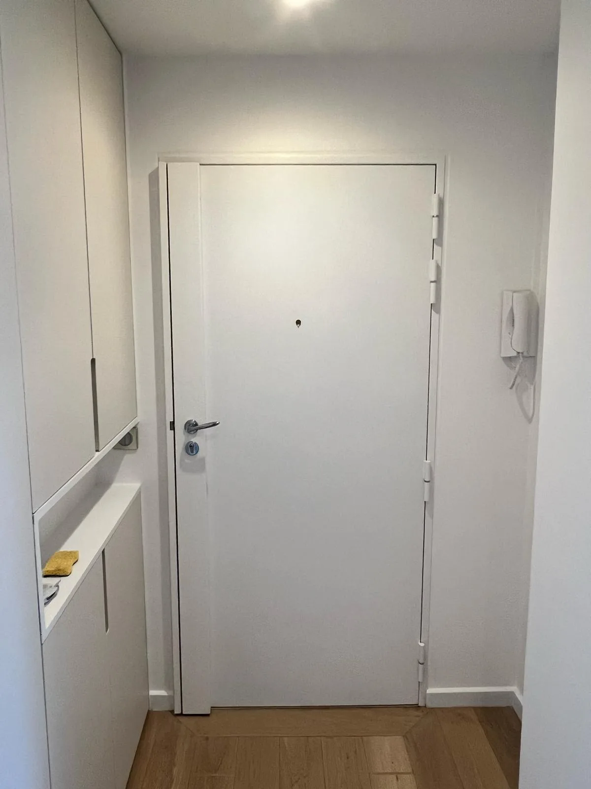 Porte blanche à bandeau caréné dans une entrée en parquet, allée Maillasson à Boulogne-Billancourt