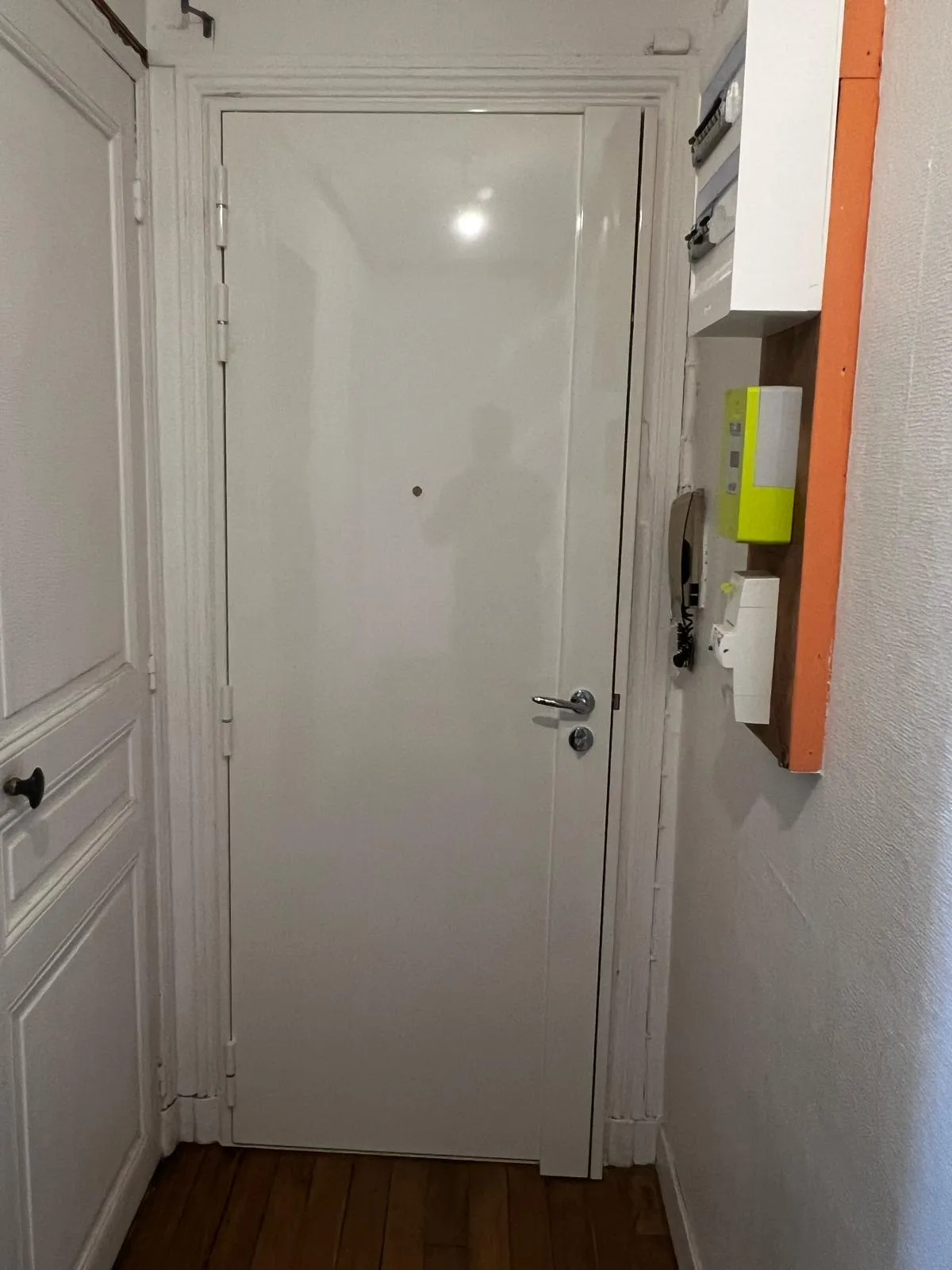 Porte blanche laquée à bandeau caréné dans une entrée avec patères, rue Ernest Renan à Boulogne-Billancourt